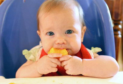 Малыш пробует кусочек фрукта