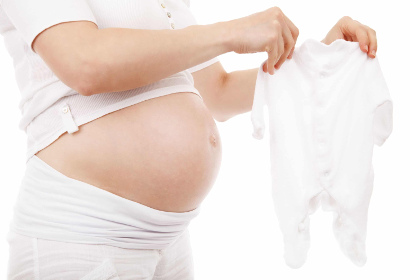 Беременная подготавливает вещи для будущего ребенка