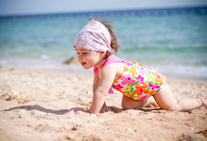 Девочка ползет по песку